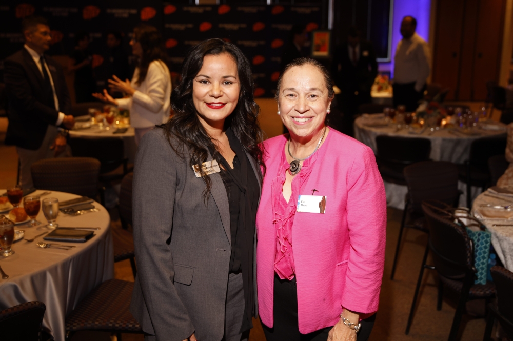 Two women smile for a photo during a formal UTEP reception.